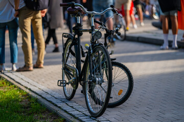 Standing bicycles in front of a crowd outside city