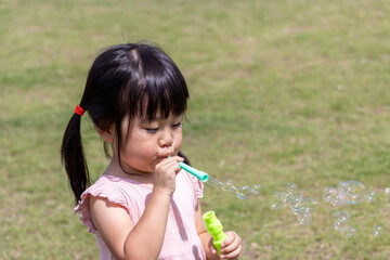 公園でシャボン玉で遊ぶ女の子（日本人、3歳）