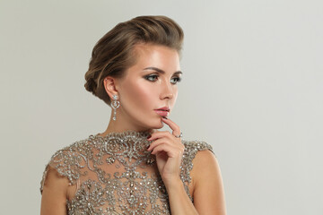 Fashion portrait of beautiful glamorous brunette model woman with makeup and fashionable luxurious diamond earring and shiny dress