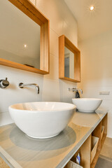 a modern bathroom with two sinks and mirror above the sink is in focus to the light coming through the window