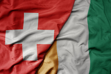 big waving national colorful flag of switzerland and national flag of cote divoire .