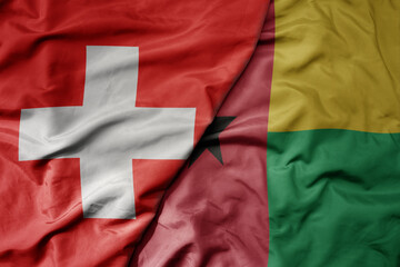 big waving national colorful flag of switzerland and national flag of guinea bissau .