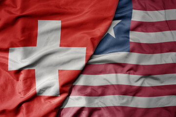 big waving national colorful flag of switzerland and national flag of liberia .