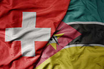 big waving national colorful flag of switzerland and national flag of mozambique .