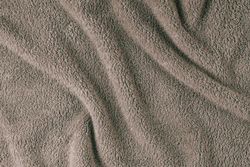Terry cloth, brown towel texture background. Wrinkled and crumped soft fluffy textile bath or beach towel material. Top view, close up.