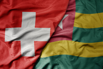 Obraz premium big waving national colorful flag of switzerland and national flag of togo .