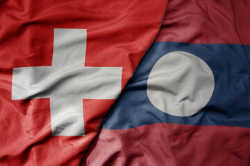big waving national colorful flag of switzerland and national flag of laos .