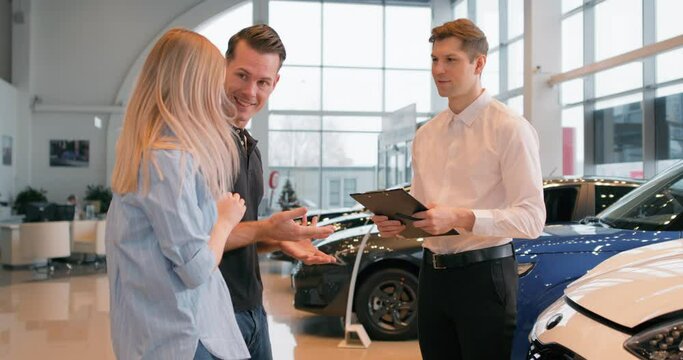 happy Caucasian young family has bought new car on Black friday Man shaking hands with trader. Success, business. couple celebrating bargain, clapping hands applauding Slow motion, successful shopping