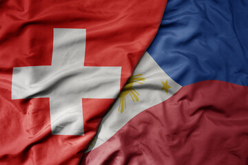 Fototapeta premium big waving national colorful flag of switzerland and national flag of philippines .