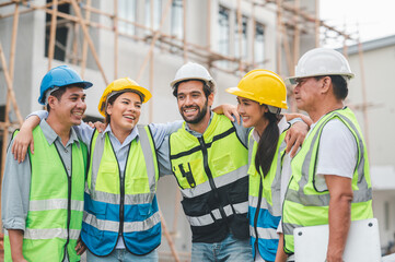 Group of happy construction team with architect engineer laughing together at building site