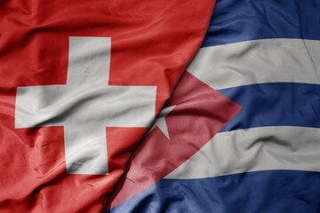 big waving national colorful flag of switzerland and national flag of cuba .