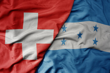big waving national colorful flag of switzerland and national flag of honduras .