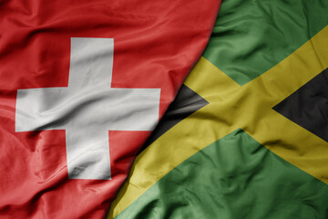 big waving national colorful flag of switzerland and national flag of jamaica .