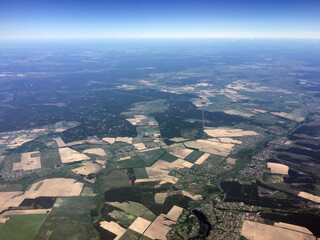 Top view of distant land surface with forests and fields. View from the plane