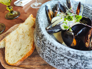 lunch at the restaurant. mussels stewed in cream sauce, garnished with herbs. served in a grey granite bowl with toasted bread