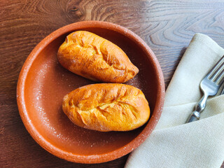 lunch at the restaurant. two pies on a brown ceramic saucer are served as a snack. Top view