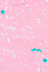 Smeared transparent gel with blue granules. On a pink background.