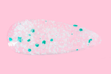 smears and drops of transparent gel with blue granules. On a pink background.