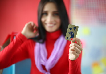 Focus on tender female hand with red manicure holding special banking utility. Joyful woman wearing trendy and fashionable outfit. Happy shopping concept