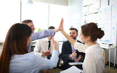 Portrait of biz people performing friendly gesture in order to celebrate important business event. Gorgeous woman doing high five in big modern office. Company meeting concept