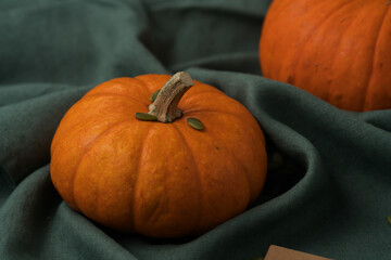 Orange pumpkin on linen napkin on wood table for seasonal background