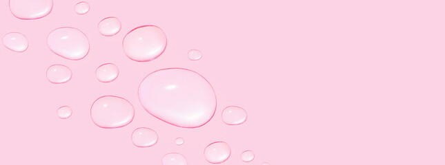 Drops of transparent gel or water in different sizes. On a pink background.