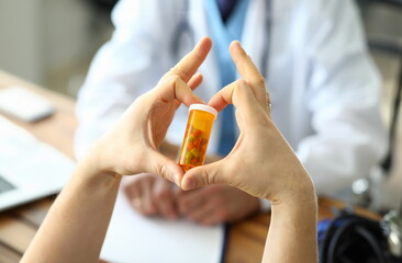 Male hand hold yellow pill jar in hospital doctor office. Cardiology treatment illness concept