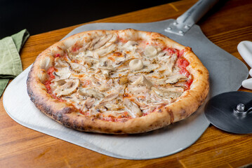 Pizza with mushrooms and chicken with tomato sauce and melted cheese.