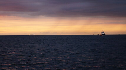 The sun sets behind the horizon and the sea ends at the horizon line