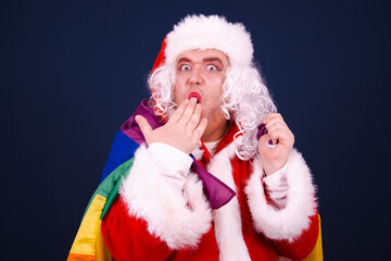 A funny drag queen enjoys life in a Santa Claus costume. Blue background.
