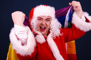 A funny drag queen enjoys life in a Santa Claus costume. Blue background.