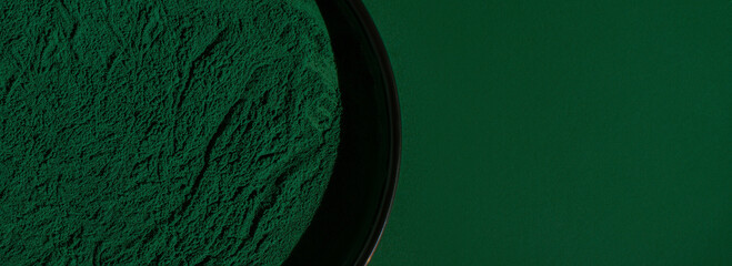 Fresh spirulina algae powder on green background, close-up, organic spirulina powder