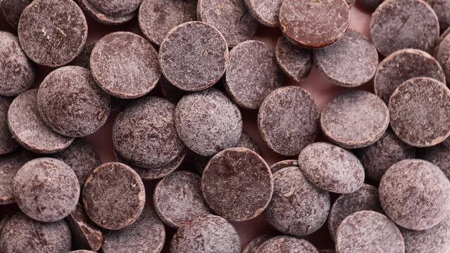 chocolate drops, rotation in circle. delicious dark chocolate chips, chocolate galettes, Turning. selective focus. chocolate background