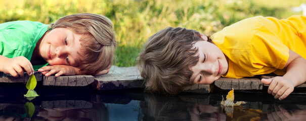 boy play with autumn leaf ship in water, children in park play with leaf in river