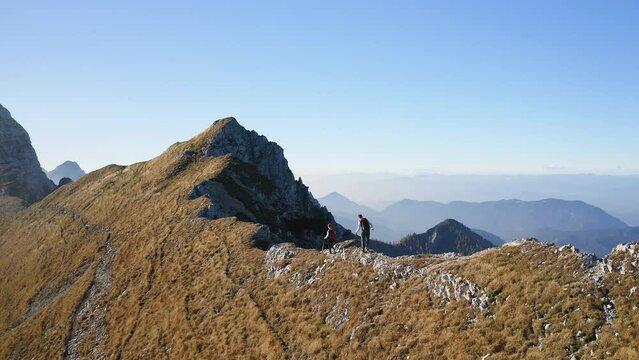 Hiking couple walking up mountain ridge on a sunny autumn day, aerial view. Life motivation, inspiration, effort, and tenacity concepts.