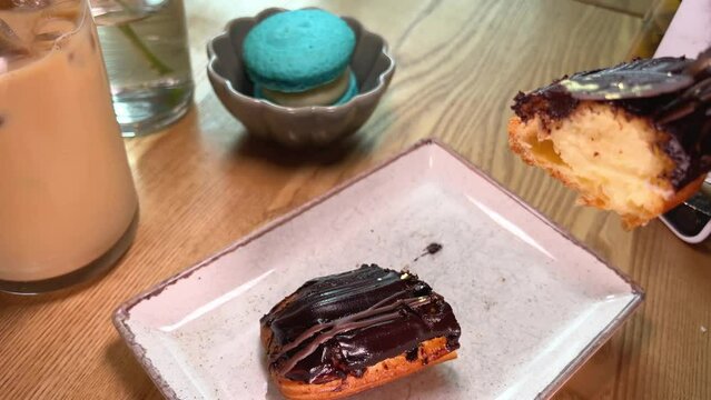 cut a piece of custard cake with butter cream poured over chocolate on white plate in a restaurant. lift the piece with a knife and fork