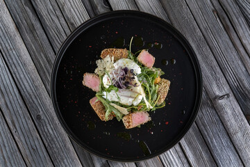 Grilled tuna steak with poached eggs and spinach. Dipped in sesame seeds.
