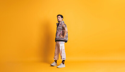 LGBTQ Man posing with pink modern clothes and yellow background