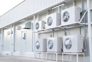 Condenser unit or compressor install side industrial plant building. Unit of central air conditioner (AC) or heating ventilation air conditioning system (HVAC). Pump and fan inside.