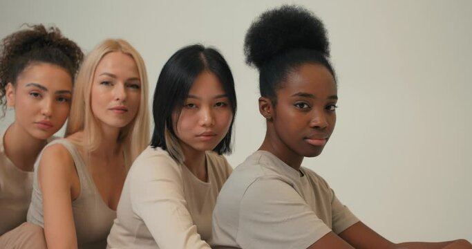 caucasian, asian black american ladies in casual wear sitting one by one, behind each other posing at camera together isolated studio background Ladies of different ethnicity appearance. lesbians