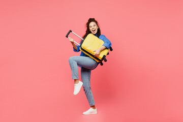 Traveler woman wears blue shirt casual clothes hold suitcase pov play guitar isolated on plain pink...