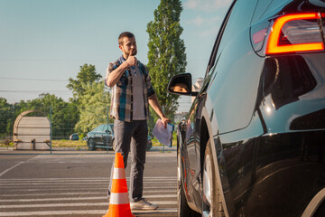 Satisfied instructor with thumbs up. Lady passing exams successfully at driving school. Traffic cones near car outdoors. Driving test, driver courses, exam concept