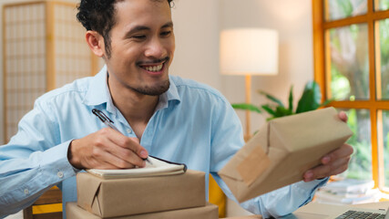 Asian Start up SME owner checking the parcel from customer via online shopping platform ,work from home e-commerce business packing and delivery concept