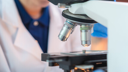Close up scientist wearing glassware working with microscope for research and analysis experiment medical biotechnology medicine pharmaceutical healthcare