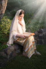 Young girl in ancient clothes reads a book