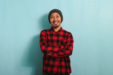 Fototapeta premium Confident young Asian man is looking at the camera with his arms crossed isolated on blue background