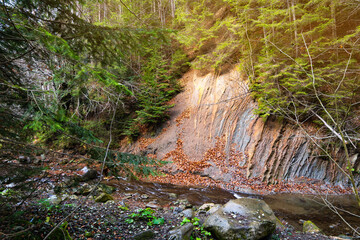A wall made of exposed rock in the autumn forest of the Ukrainian Carpathians. Mountain river....