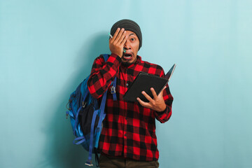 Young Asian student looks shocked after realizing he forgot to study before the exam blue background