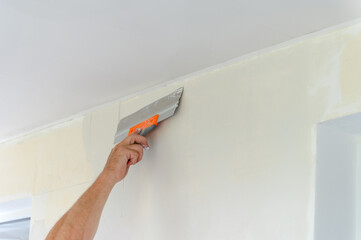 Worker trowels putty on drywall with finishing putty