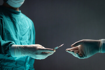 Surgeon doctor holding surgical scalpel and passing surgical equipment to each other in operating...
